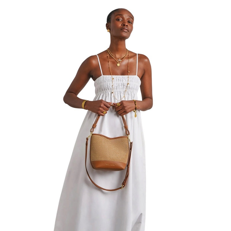Katie Loxton Sorrento Bucket Bag Natural Raffia Cognac KLB4455 held by model