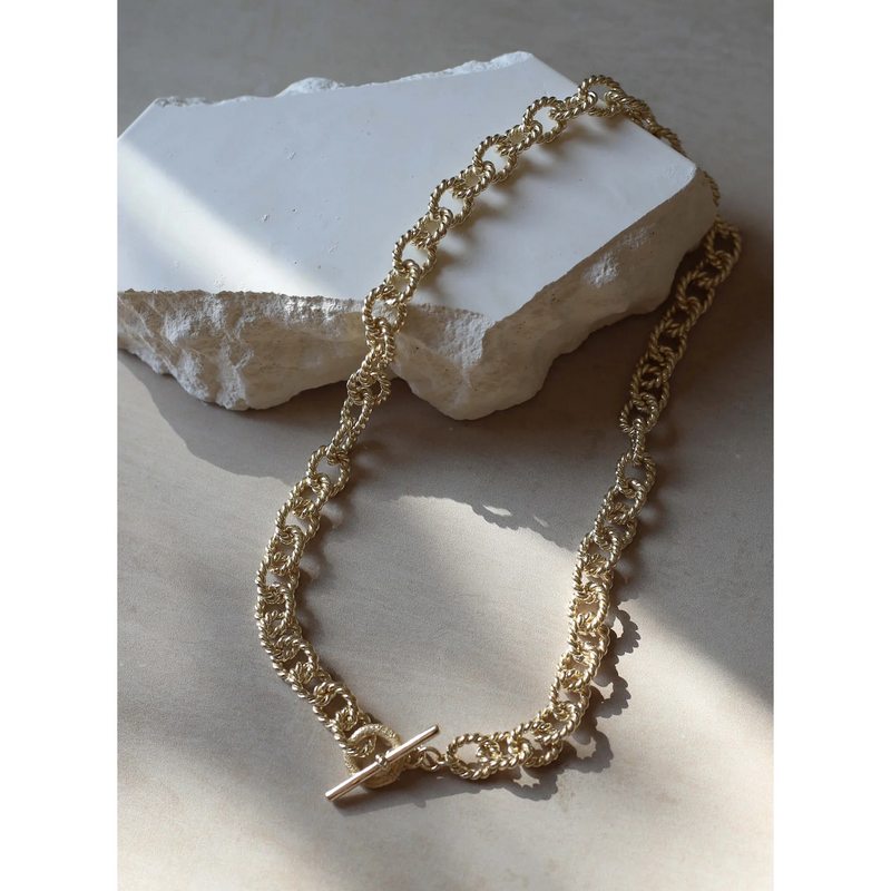 Tutti & Co Twist Necklace Gold NE691G on stone